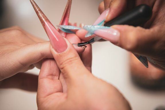 Nail Services Picture shows nail technician applying product to a clients nails.